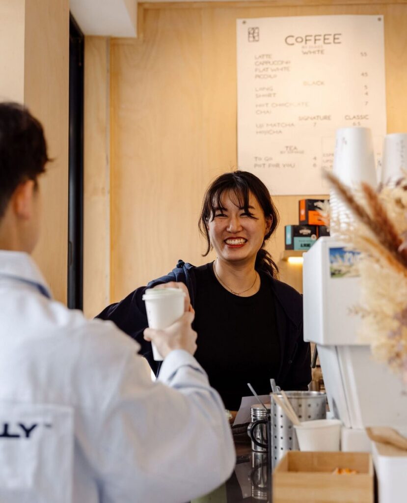 A Yuku Do team member handing a coffee across the counter