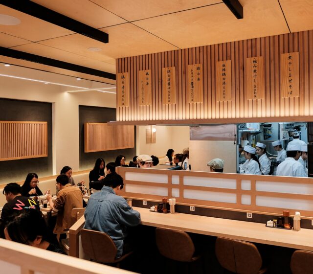 Guests eating at the Ginza Kagari counter, with chefs working in the open kitchen behind