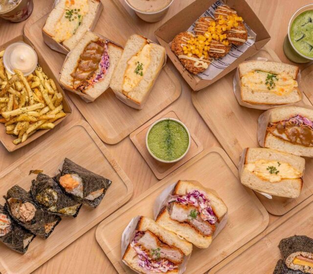 A spread of Yuku Do sandos, onigiri, fries and matcha drinks on wooden trays