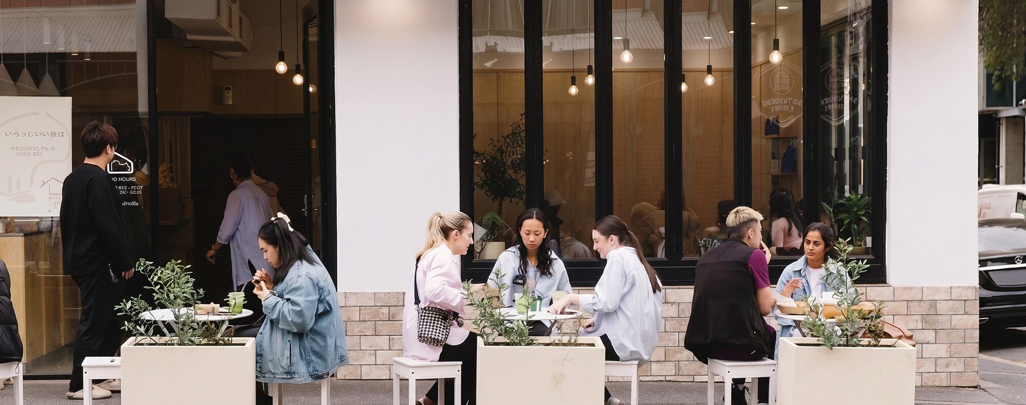 Guests eating at streetside tables outside the Yuku Do shopfront